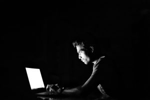 暗い場所でパソコンを触る男性